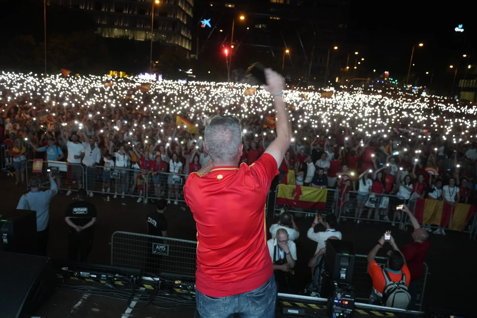 Alex Parreño de espaldas saludando a la plaza de Colón llena de luces